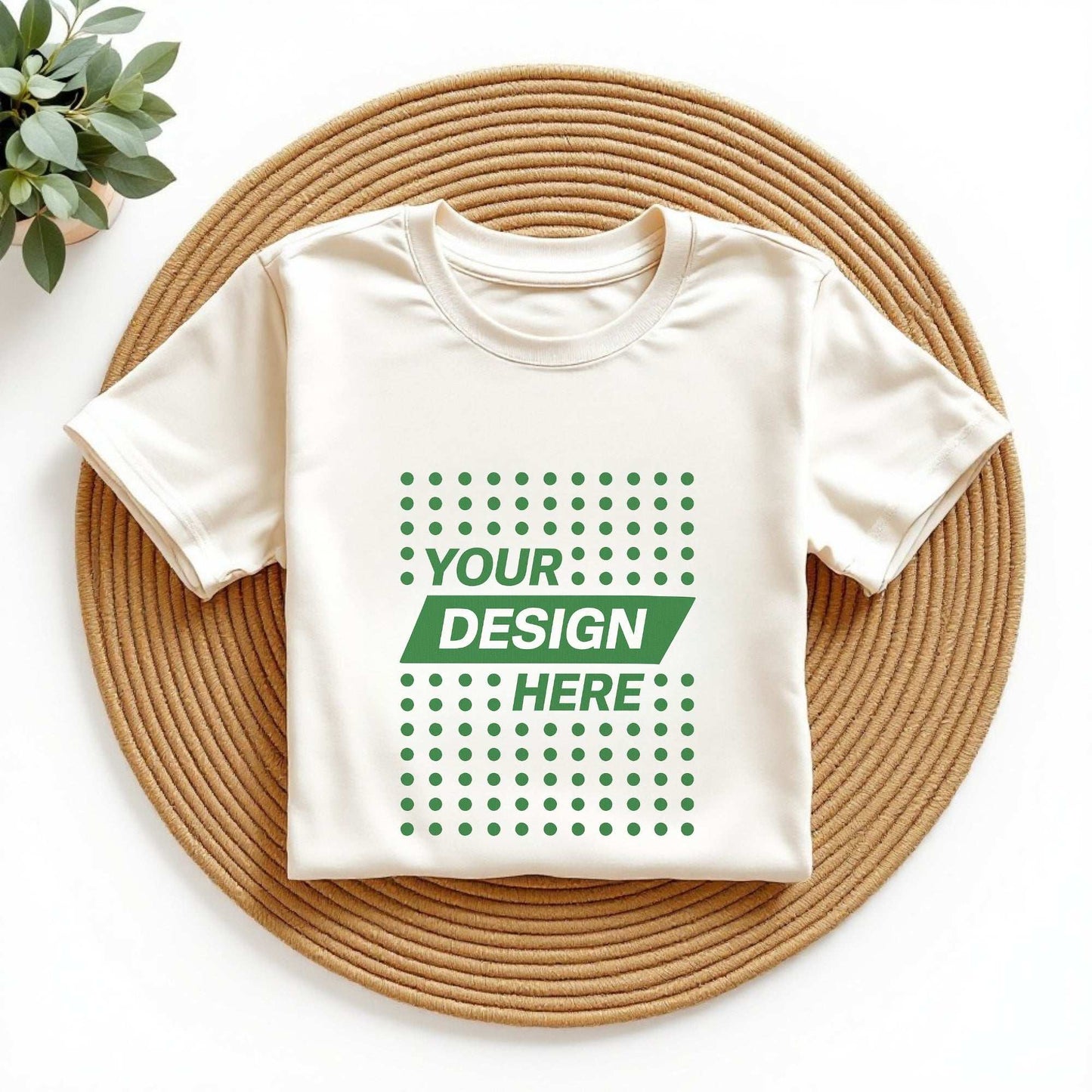 Flat lay of a beige custom T-shirt with "Your Design Here" print, displayed on a woven mat – promoting personalized T-shirt printing and custom apparel in Canada by CZORZ.